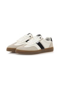 Zapatillas en cuero beige y blanco con detalles en negro. Cuenta con una suela texturizada y cierre con cordones. Paneles suaves y rayas contrastantes.