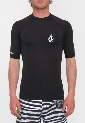 Maglietta a maniche corte nera per il surf con un design aderente, caratterizzata da un logo bianco sul lato sinistro del petto e cuciture a contrasto lungo le cuciture.