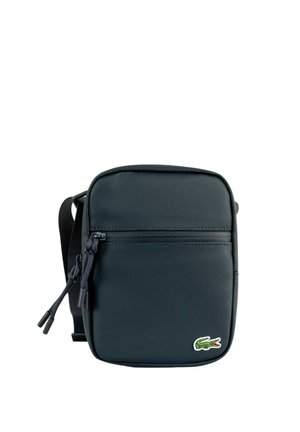 Sac bandoulière noir texturé avec poche zippée frontale et logo crocodile vert en bas à droite.