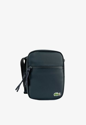 Zwarte gestructureerde crossbodytas met voorvak met rits en groen krokodillenlogo rechtsonder.