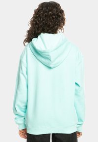 Mintgroene oversized hoodie met een koord in de capuchon, gemaakt van zachte katoen en met geribbelde manchetten. Gladde textuur, zonder zichtbare patronen of accenten.