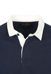 Marineblauwe poloshirt met een witte kraag, voorzien van een knoop en een subtiele textuurstof. Label zegt "STEPPIN' OUT."