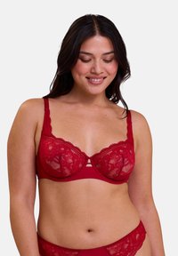 Soutien-gorge en dentelle rouge avec armatures, bretelles réglables et motifs floraux. Comprend un détail central avec trois découpes horizontales.
