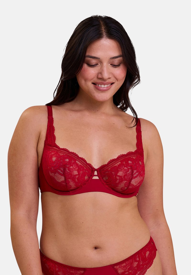 Soutien-gorge en dentelle rouge avec armatures, bretelles réglables et motifs floraux. Comprend un détail central avec trois découpes horizontales.