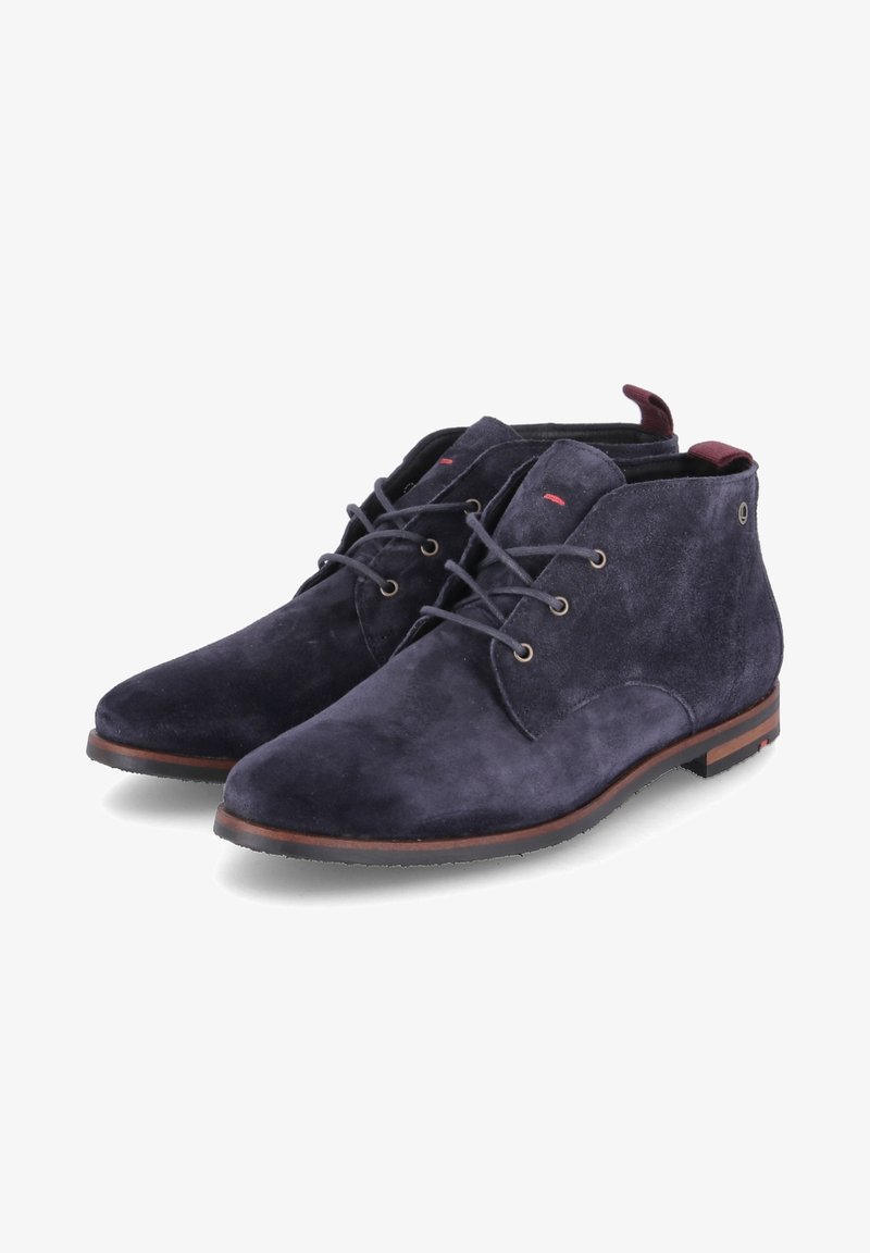 Paire de bottines en daim bleu marine à lacets avec semelles marron et languettes de talon rouges, présentant un design élégant et raffiné.