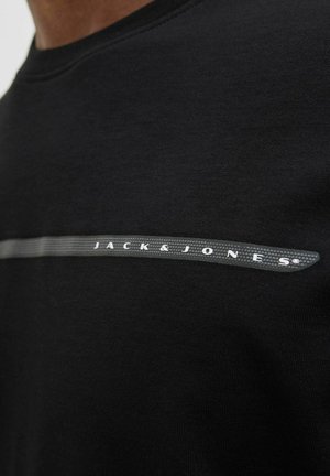Black cotton t-shirt with a crew neck, featuring a grey horizontal stripe and "JACK & JONES" logo in white. Smooth texture.