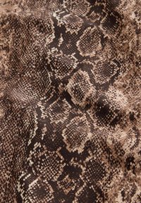 Tissu imprimé animal, présentant un motif texturé ressemblant à de la peau de serpent dans des nuances de marron et beige sur un fond foncé.