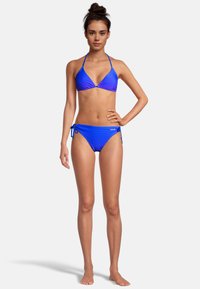 Blauwe bikini met stippen, gemaakt van rekbare stof, met een triangeltop met halterbandjes en een zijstrik-bovenkant met bijpassende kleuraccenten.