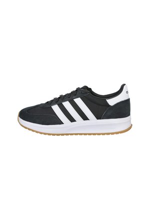 Zapatilla Adidas en blanco y negro con tres franjas blancas, diseño con cordones, suela blanca acolchada y suela exterior de color goma, vista de lado.