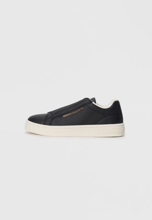 Black leather slip-on sneaker with white sole, gold "Armani Exchange" logo on side, and minimalist stitching detail.