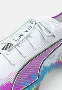 White sports shoe with a textured upper, neon laces, and a vibrant graphic pattern in purple, pink, and blue along the sole.