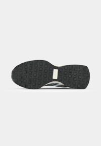 Black rubber sole with a textured pattern of squares; features a sleek design with a white midsole; athletic style.