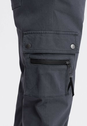 Pantalones cargo gris oscuro con un bolsillo lateral que cuenta con un zipper negro, botones plateados y acentos cosidos. Tejido duradero con una textura suave.