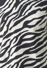 Tkanina s uzorkom crno-bijelih zebra pruga, glatke teksture, sa valovitim crtama i kontrastnim bojama, namijenjena za odjeću.