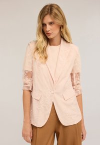 Hellrosa Blazer mit floralem Spitzenüberzug, strukturierte Form, Reverskragen, Knopfverschluss und transparente, gestickte Ärmel. Taillierte Passform.