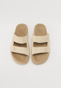 Beige tvåbandsandaler med en mjuk mockaöverdela, öppen tå och formad innersula. Har synlig varumärkeslogotyp och sömnadsdetalj.