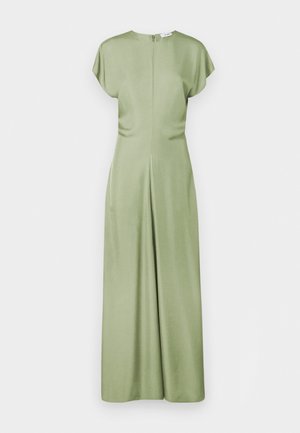 Zaļš, gluds auduma kombinezons ar īsām piedurknēm, augstu kakla izgriezumu un rāvējslēdzēju aizmugurē. Tam ir brīvs piegriezums un plaši mati.