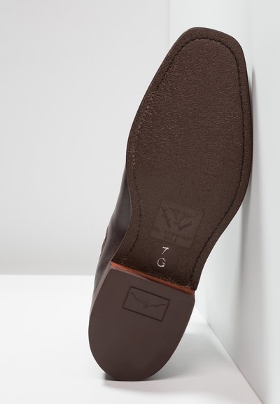 Brown leather shoe sole with textured surface, featuring an oil-resistant label, size "7 G," and a decorative logo imprint.