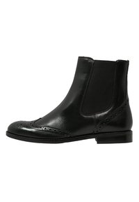 Botín negro de cuero hasta el tobillo con detalles de brogue, paneles laterales elásticos y un bajo tacón apilado. Textura suave y diseño estilizado.