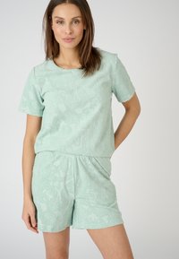 Mintgroene set van twee delen, gemaakt van textuurstof, met een top met korte mouwen en shorts met een bloemmotief en gekartelde randen.