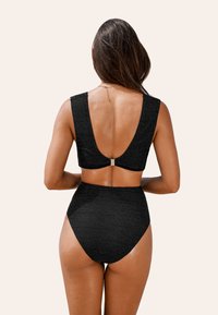 Ensemble de bikini noir avec un design texturé, dos nu et bretelles larges, accompagné d'un bas taille haute.