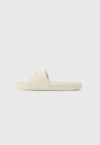 Lys beige sandaler med bred overdel og flat såle, med en jevn tekstur og minimalistisk design.