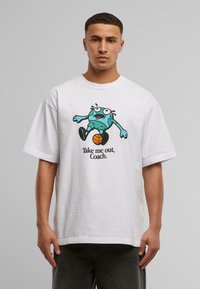 T-shirt en coton blanc avec un grand graphique de dessin animé d'un personnage bleu jouant au basket-ball, accompagné du texte "Emmène-moi dehors, Coach."