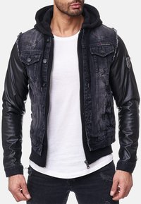 Denim en leren jack, donkergrijs met zwarte mouwen, rits aan de voorkant, twee borstzakken, versleten details op de schouders en een logo patch op de mouw.