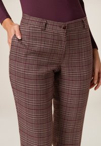 Pantalons à carreaux en bourgogne et rose clair, avec une texture lisse, une coupe classique, des poches avant et un détail de bouton à la taille.