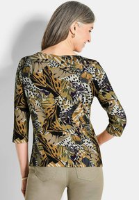 Bunt gemusterte Bluse mit floralem und tierischem Design, gefertigt aus einem weichen Stoff, mit Dreiviertelärmel und rundem Halsausschnitt.