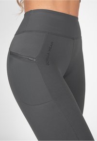 Hoge taille grijze leggings met een gladde textuur, uitgerust met een zijzak met rits en subtiele "GORILLA WEAR" merknaam op de dij.