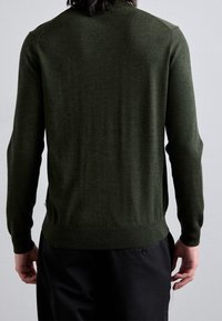 Suéter de punto en verde oscuro con un diseño ajustado, mangas largas, puños acanalados y un escote redondo, que presenta una textura suave y detalles de costura sutiles.