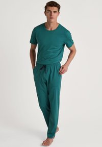 Teal T-shirt met korte mouwen en een ronde hals, gecombineerd met bijpassende joggerpants met een elastische tailleband en zijzakken.