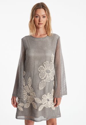 Robe grise à manches longues avec une coupe ample, arborant un motif floral en dentelle crème ; tissu léger et texturé avec un col rond.