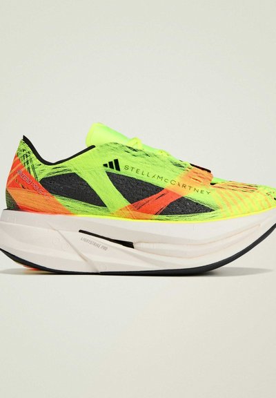 Baskets de course jaune fluo avec des accents noirs et rouges, dotées d'un dessus texturé, d'une semelle intermédiaire légère et d'une semelle incurvée pour une performance améliorée.