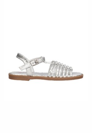 Sandal de tiras plateado con suela plana marrón, que presenta una correa con hebilla y múltiples bandas horizontales en la parte delantera, acabado metálico brillante.