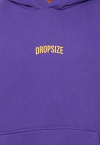 Paarse hoodie van zachte stof met een kangoeroezak en het woord "DROPSIZE" in gele tekst op de borst.