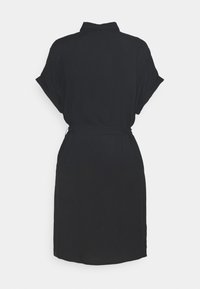 Robe noire à manches courtes avec col et ceinture à la taille, vue de dos sur un fond clair uni.