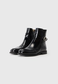 Botas de couro pretas até ao tornozelo, com um acabamento liso, fecho de correr e uma tira decorativa com uma fivela prateada. Sola de borracha plana.