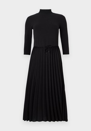 Vestito nero con una parte superiore aderente a coste, colletto alto e maniche a tre quarti. Gonna plissettata con vita regolabile tramite cordoncino.