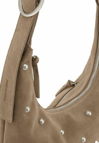 Borsa a spalla in suede marrone con borchie argentate, presenta una forma arrotondata, chiusura con zip e una tracolla piatta con un accento di anello metallico.