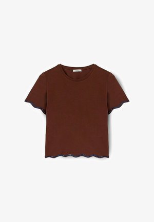 Camiseta marrón de manga corta con un dobladillo ondulado. Acentuada con un ribete a rayas azul y blanco a lo largo de las mangas y el dobladillo. Fabricada con tejido suave.