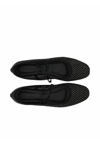 Zapatos planos negros hechos de tela texturizada, con punta afilada, lazo decorativo en la parte frontal y pequeños studs plateados en la parte superior.