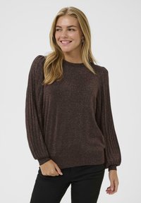 Tumepruun pullover-sweater läikiva viimistlusega. Omab ribatekstiilis kupli põhimõttega varrukaid ja ümmargust kaela. Pehme tekstuur ja mugsas lõige.