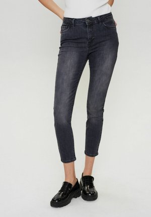 Dark wash skinny jeans with a high waist, ankle length, and minimal fading. Paired with chunky black loafers for contrast.