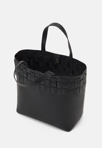 Svart tote väska i vävd och slät syntetisk material. Den har dubbla handtag och en säker knappstängning upptill.