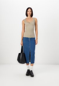 Beige ribbatoppi, jossa on pitsireunus, yhdistettynä farkkuhameeseen, jossa on etureikä. Musta olkalaukku ja paksupohjaiset loafertossut täydentävät asukokonaisuuden.