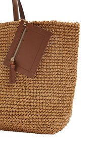 Sac fourre-tout en paille tissée avec des poignées en cuir marron et une petite pochette en cuir amovible avec zip à l'avant.