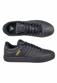 Czarne buty sportowe z gładką skórzaną cholewką, teksturowanymi akcentami, okrągłym noskiem, płaską gumową podeszwą i trzema paskami w designie. Złoty detal z logo.