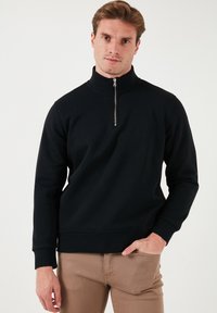 Black pullover sweatshirt with a high neck and quarter zipper, made of soft material. Features long sleeves and ribbed cuffs and hem.